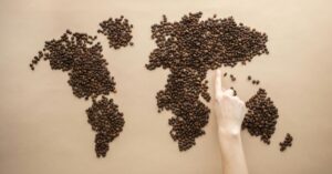 Crop person pointing at world map of coffee beans