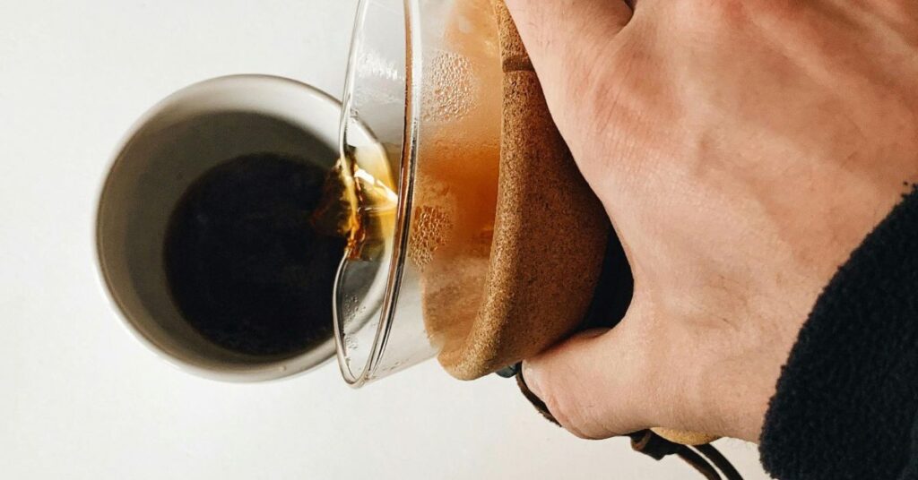 Close-Up Photo of a Person Pouring Brewed Coffee into a Cup