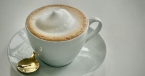 A cup of foamy coffee latte in a white mug.