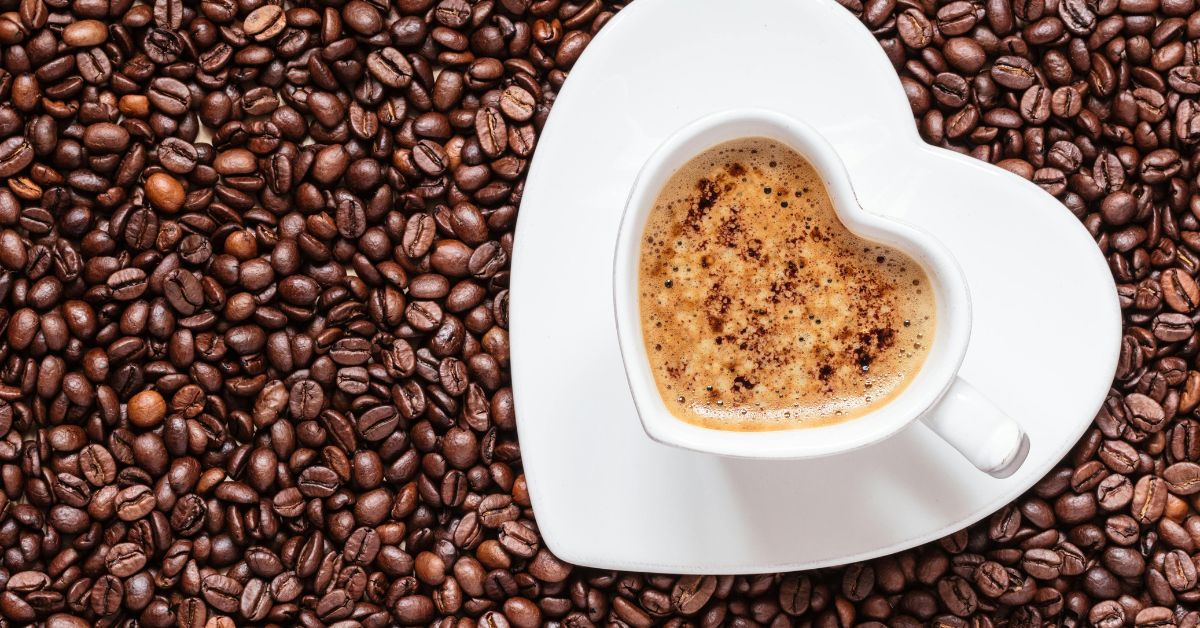 Espresso served in a heart-shaped cup amidst a bed of coffee beans, showcasing rich coffee aroma and style