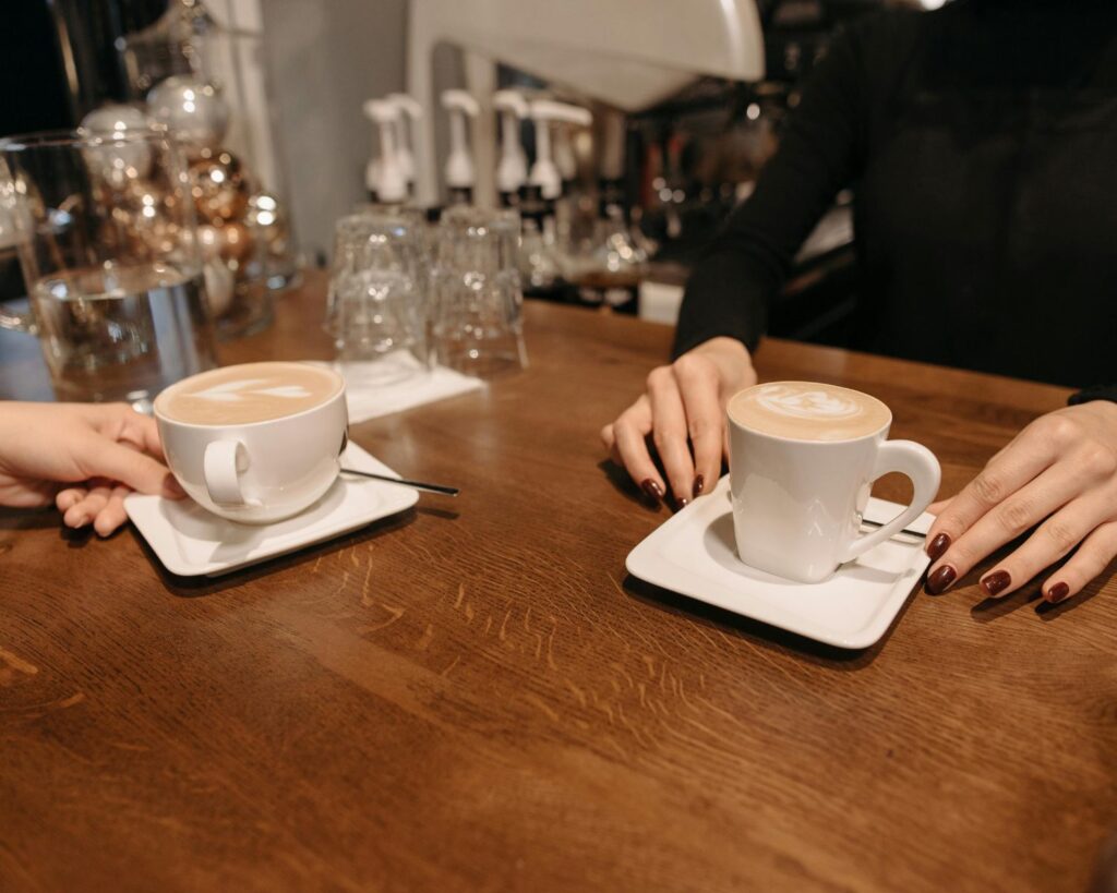 Two lattes with foam art on wooden counter.
