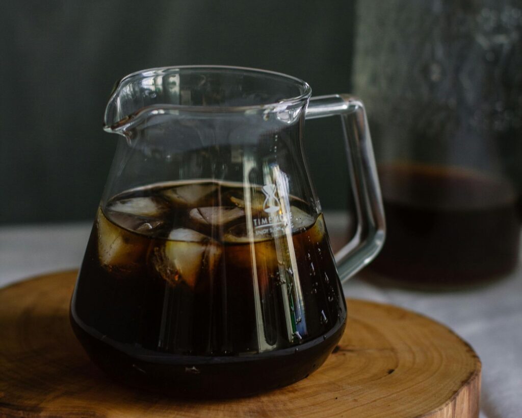 Clear Glass Pitcher With Cola and Ice on Wooden Chopping Board
