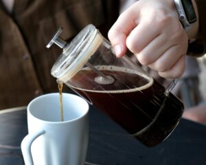 A Person's Hand Pouring Coffee into a White Cup