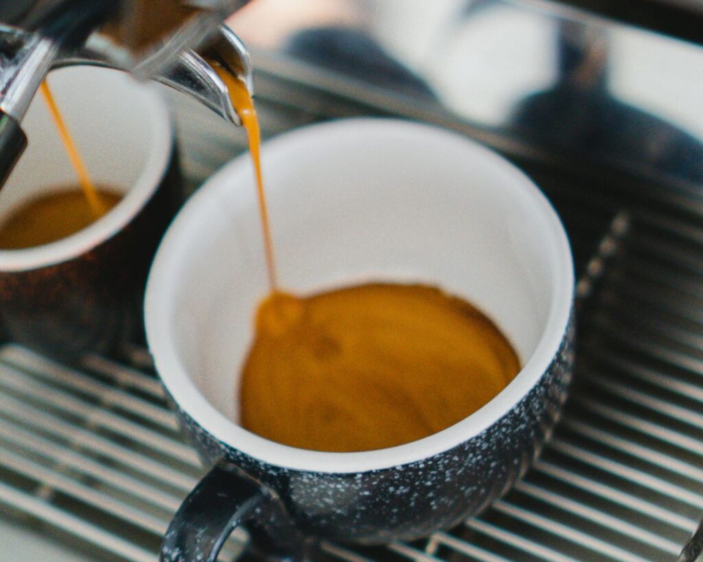 Coffee from machine pouring over cup