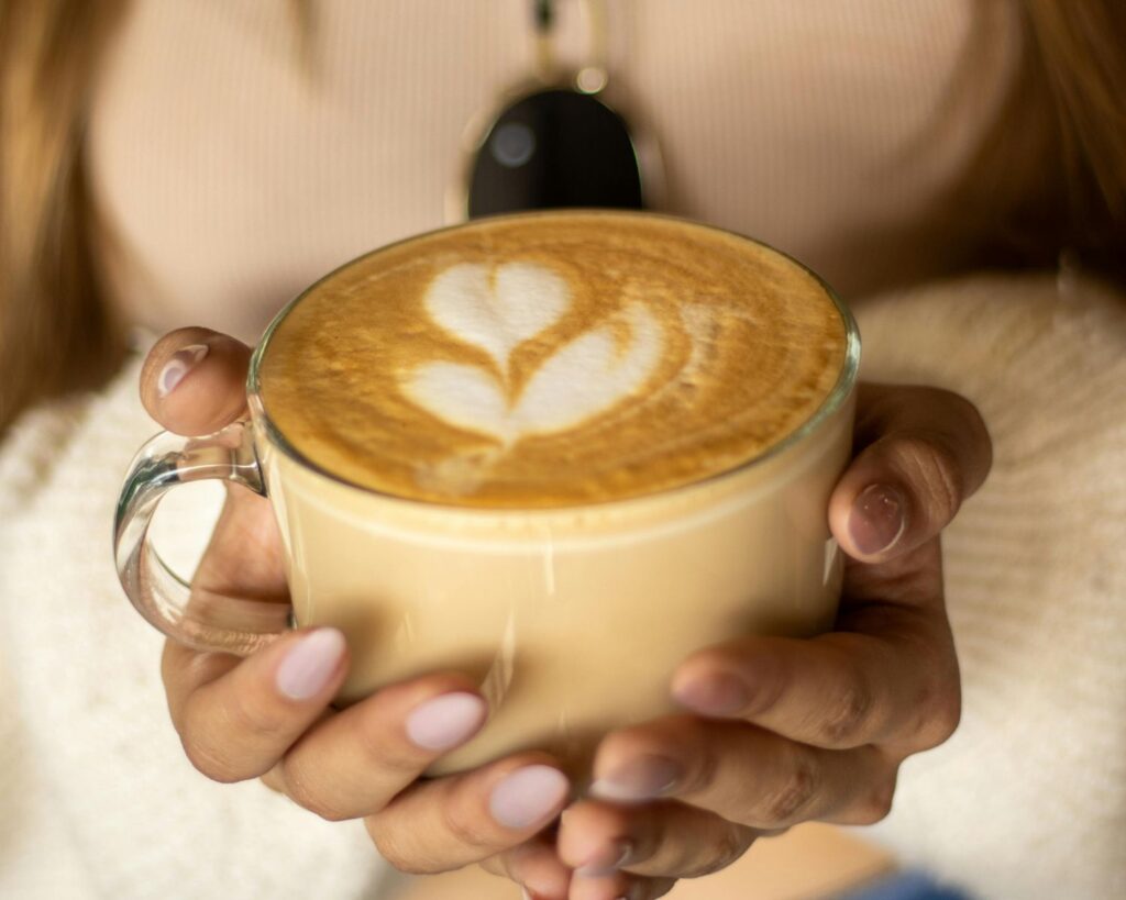 A woman holding a large cup of coffee latte