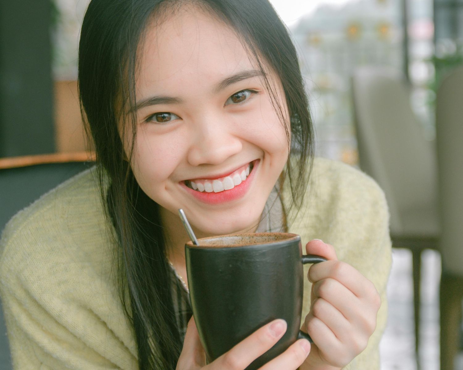 A Smiling Woman Holding Black Ceramic Mug