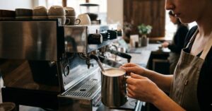 Barista frothing milk with an espresso machine.